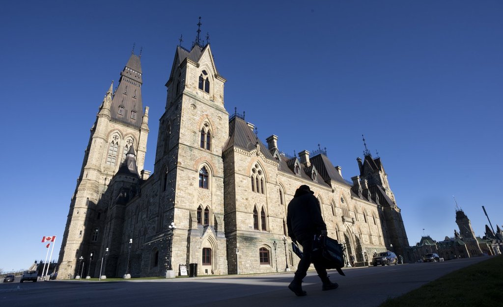 A worker walks past the West Block as Parliament returns on Monday, Nov. 22, 2021, in Ottawa. THE CANADIAN PRESS/Adrian Wyld.