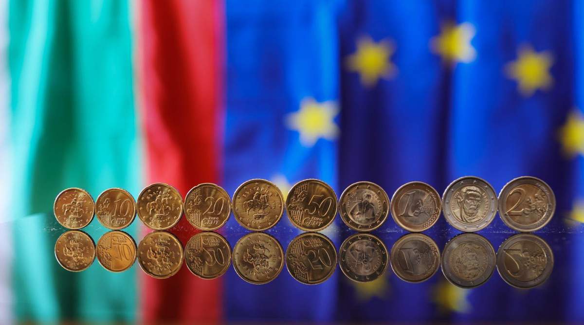 New Euro coins with Bulgarian symbols reflected in a table seen backdropped by Bulgarian and EU flag, Sofia, Tuesday Dec. 30, 2025. (AP Photo/Valentina Petrova).