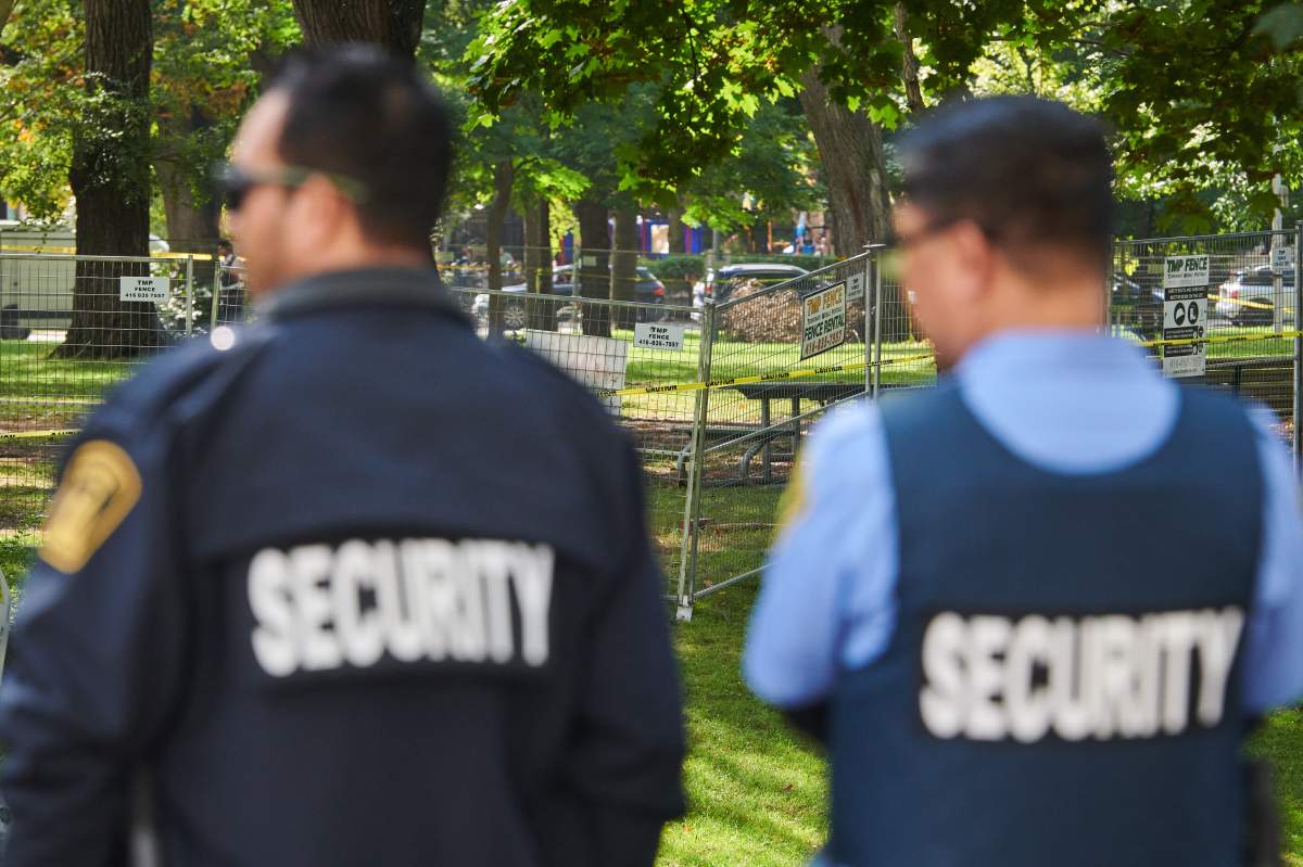 Security stand by newly-erected fencing after workers cleared an encampment at Dufferin Grove park in Toronto, on Friday, Sept. 26, 2025. 
