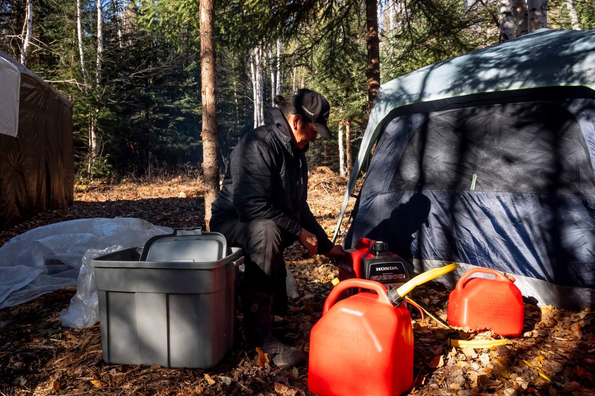 James Kataquapit of Attawapiskat First Nation fills a generator with fuel at an encampment on the river bank of the Attawapiskat river, east of Neskantaga, Ont., on Saturday, Oct., 25, 2025. 