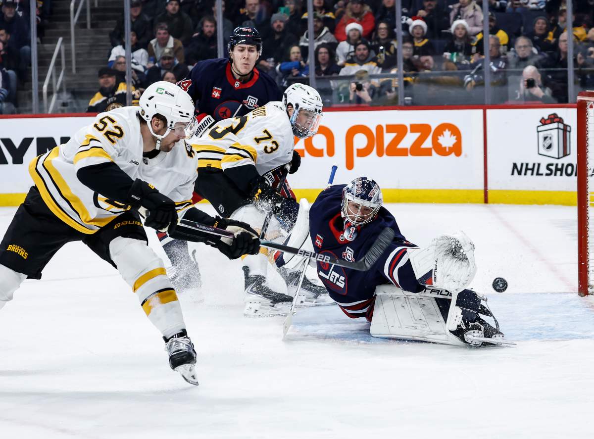 Boston Bruins' Sean Kuraly (52) scores on Winnipeg Jets goaltender Eric Comrie (1) during first period NHL action in Winnipeg on Thursday, December 11, 2025. THE CANADIAN PRESS/John Woods.