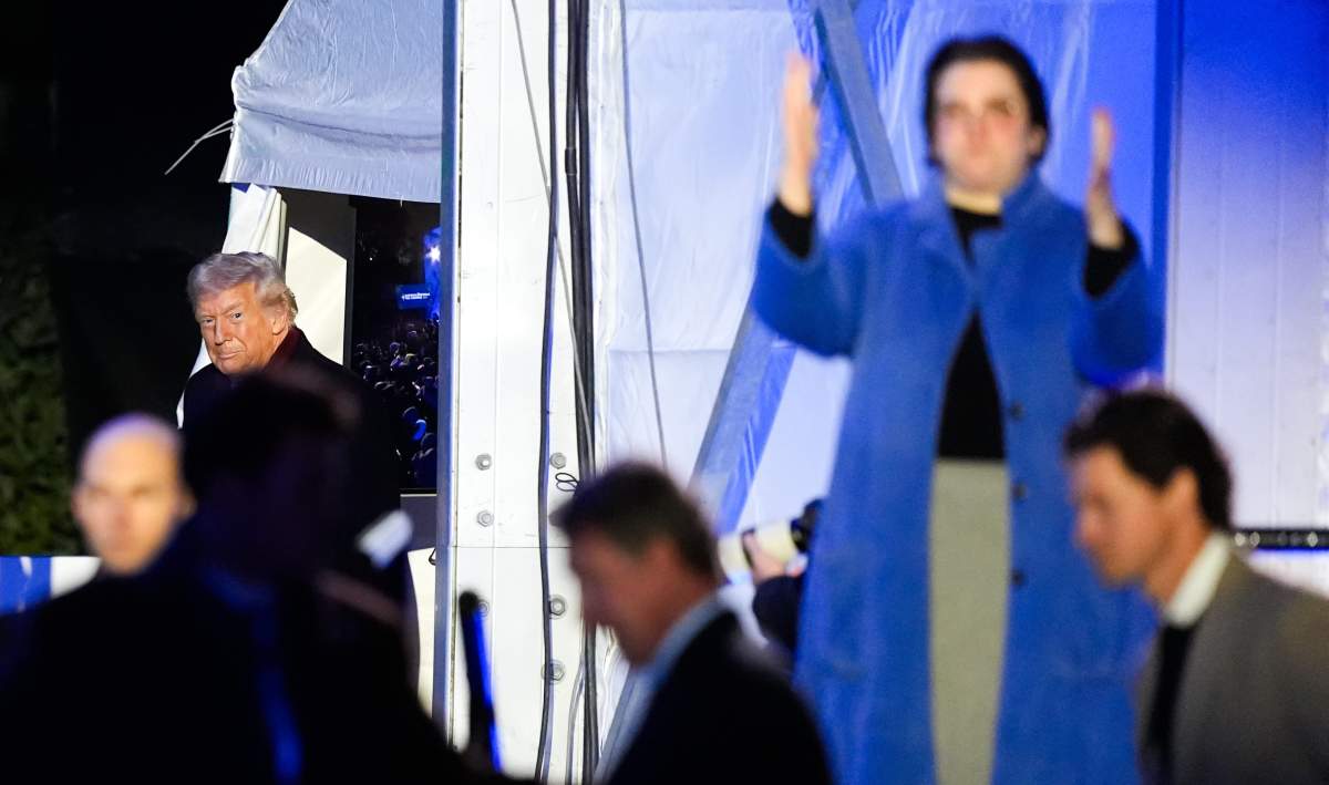 An American Sign Language interpreter, right, signs as President Donald Trump arrives for the lighting of the National Christmas Tree on the Ellipse, Thursday, Dec. 4, 2025, near the White House in Washington. (AP Photo/Julia Demaree Nikhinson).