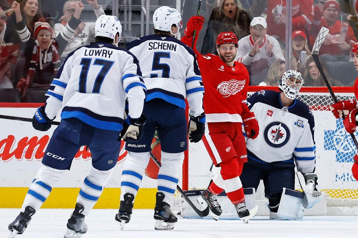 Detroit Red Wings right wing Alex Debrincat, second from right, celebrates a goal scored by center Dylan Larkin against Winnipeg Jets goaltender Connor Hellebuyck, right, during the first period of an NHL hockey game, Wednesday, Dec. 31, 2025, in Detroit. (AP Photo/Duane Burleson).