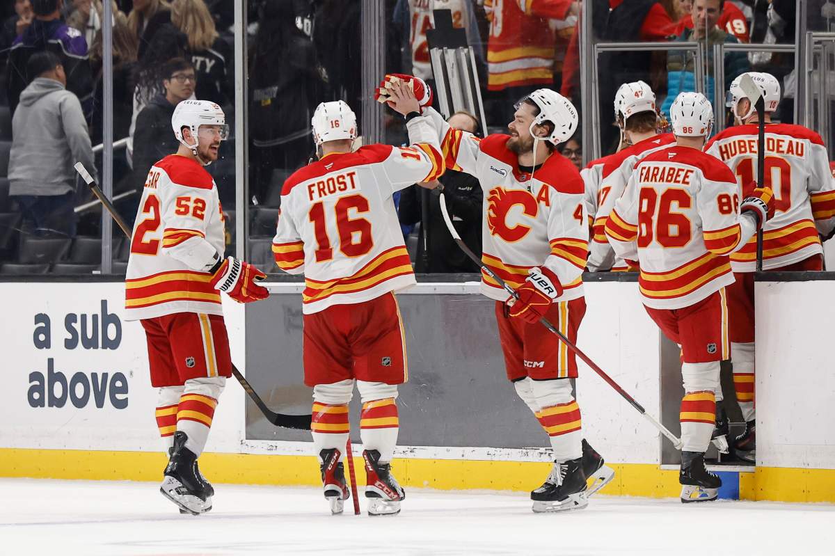 Calgary Flames center Morgan Frost (16) is greeted by teammates after scoring the game winning goal in overtime of an NHL hockey game Saturday, Dec. 13, 2025, in Los Angeles.