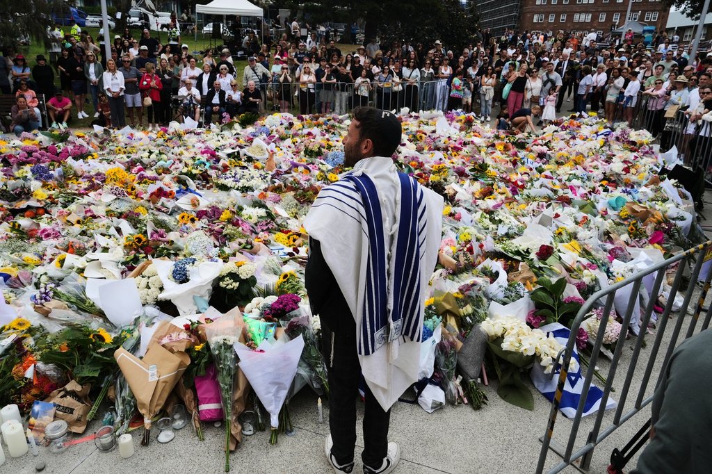 Rabbi Yossi Friedman speaks to people gathering at a flower memorial by the Bondi Pavilion at Bondi Beach on Tuesday, Dec. 16, 2025, following Sunday's shooting in Sydney, Australia.