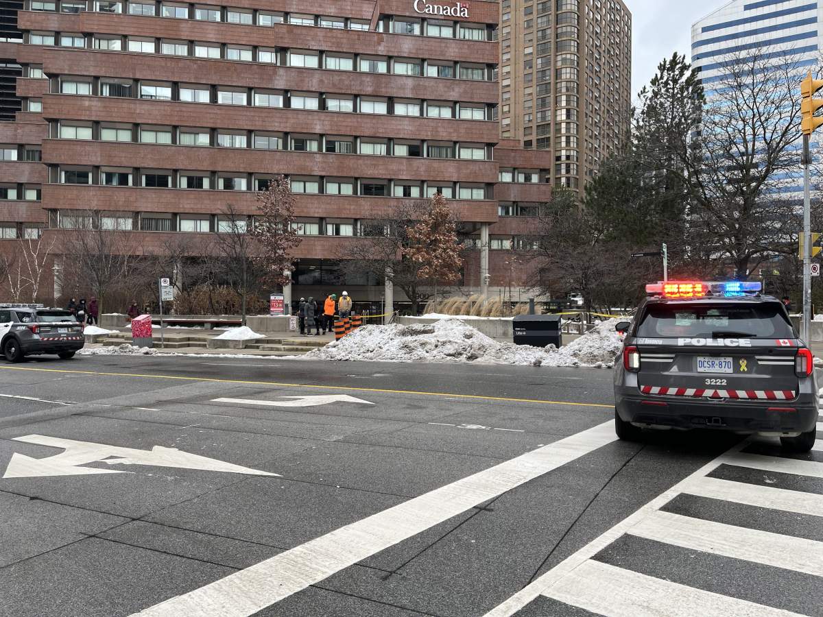 A Toronto police car sits outside a federal government building after a fire erupted inside. A man is in custody and Toronto Fire says the blaze is being investigated as a suspected arson.