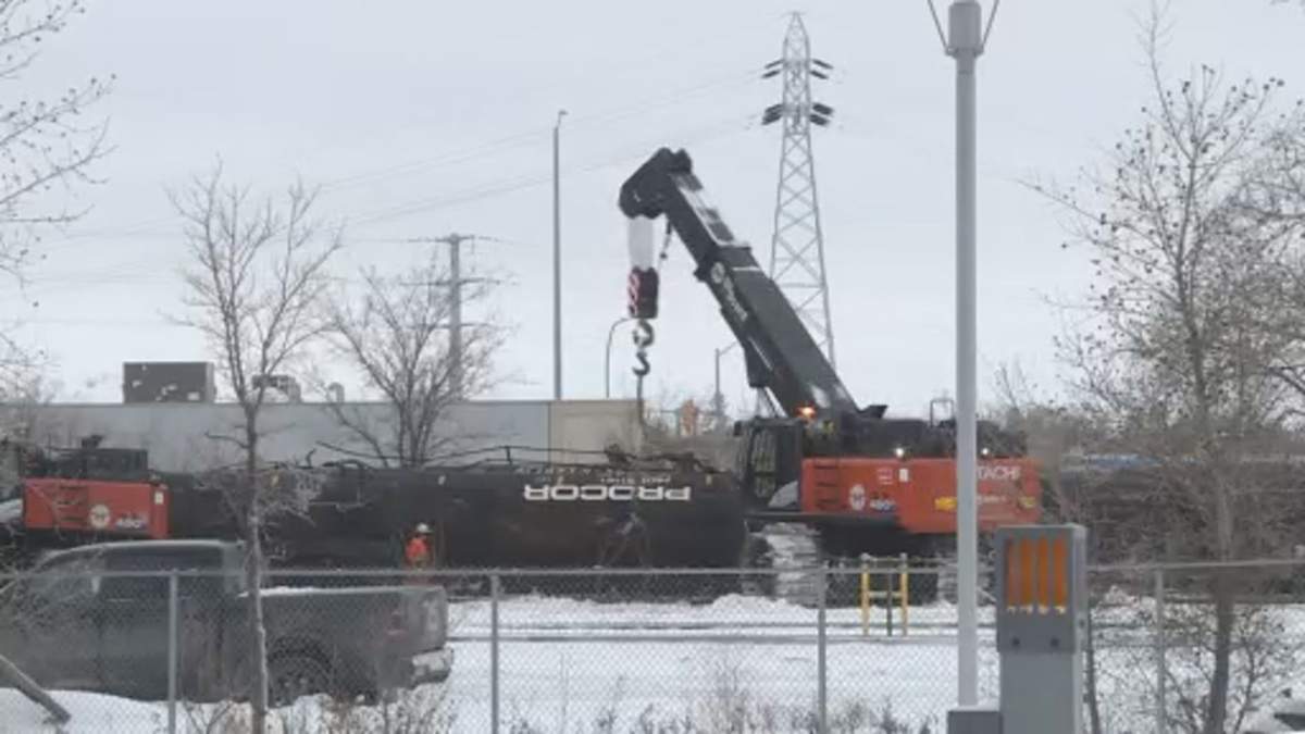 A CN Rail car sits on its side as a crane works to lift it upright after a derailment in Winnipeg on Dec. 28. 