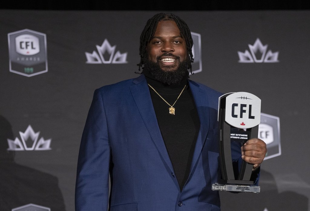Most outstanding offensive linesman Stanley Bryant of the Winnipeg Blue Bombers, holds up his trophy during the CFL Awards in Regina, Thursday, Nov. 17, 2022. Bryant will return for a 14th CFL season and ninth with Winnipeg after signing a one-year contact extension with the Blue Bombers. THE CANADIAN PRESS/Paul Chiasson.