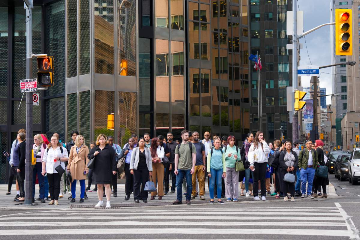 Commuters wait at an intersection outside Toronto's Union Station on Tuesday, Aug. 26, 2025.