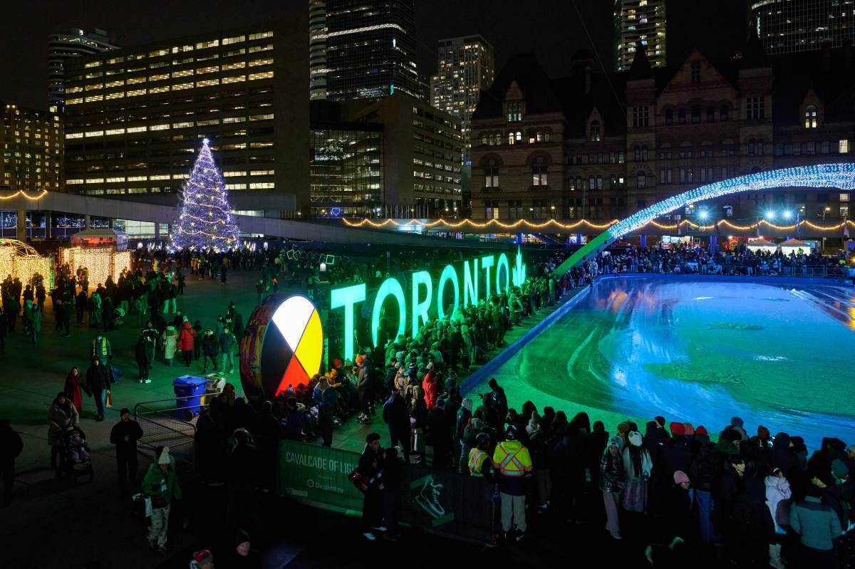 Visitors stand by the Toronto sign as they wait for the ice to be resurfaced on the opening night of the annual Cavalcade of Lights at Nathan Phillips Square, in Toronto, on Saturday, Nov. 29, 2025. 