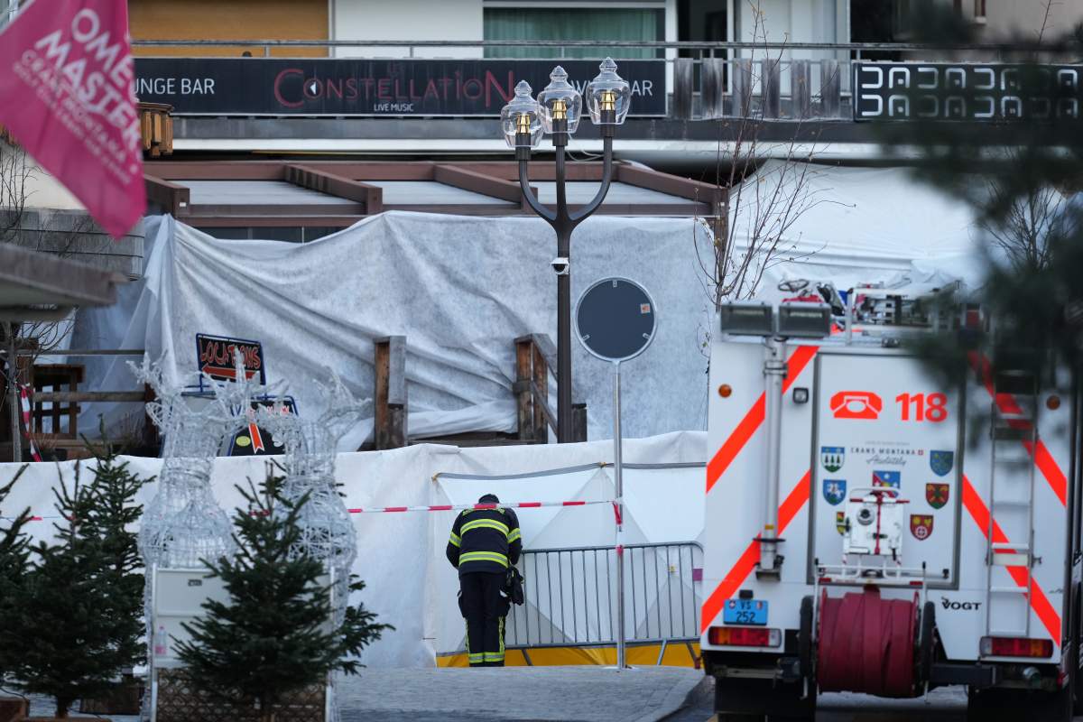 A fireworker watches the sealed off Le Constellation bar, where a devastating fire left dead and injured during the New Year’s celebrations in Crans-Montana, Swiss Alps, Switzerland, Friday, Jan. 2, 2026.