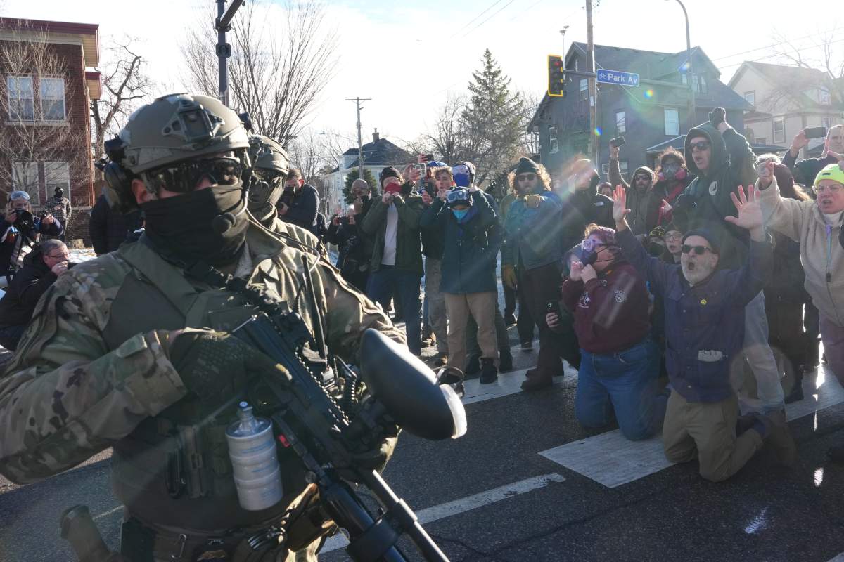 Protesters block the road as Federal agents try to leave Tuesday, Jan. 13, 2026, in Minneapolis.