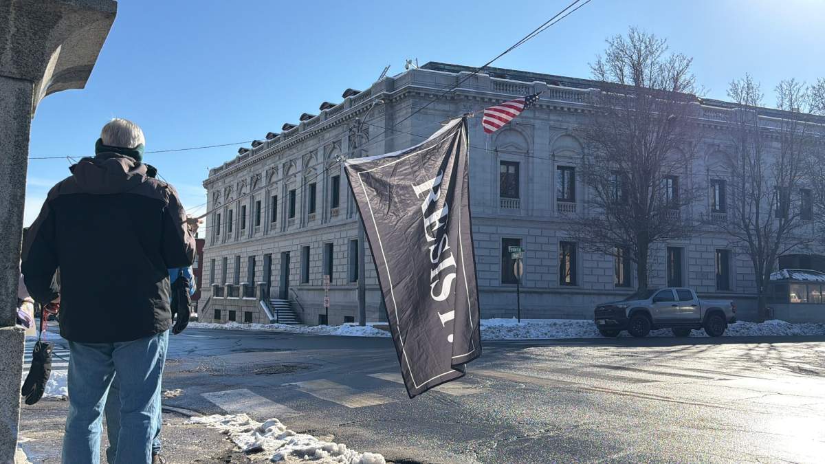 A protester holds a "Resist" flag in front of federal court in Portland, Maine as Immigration and Customs Enforcement conduct operations in the state, Thursday, Jan. 22, 2026.