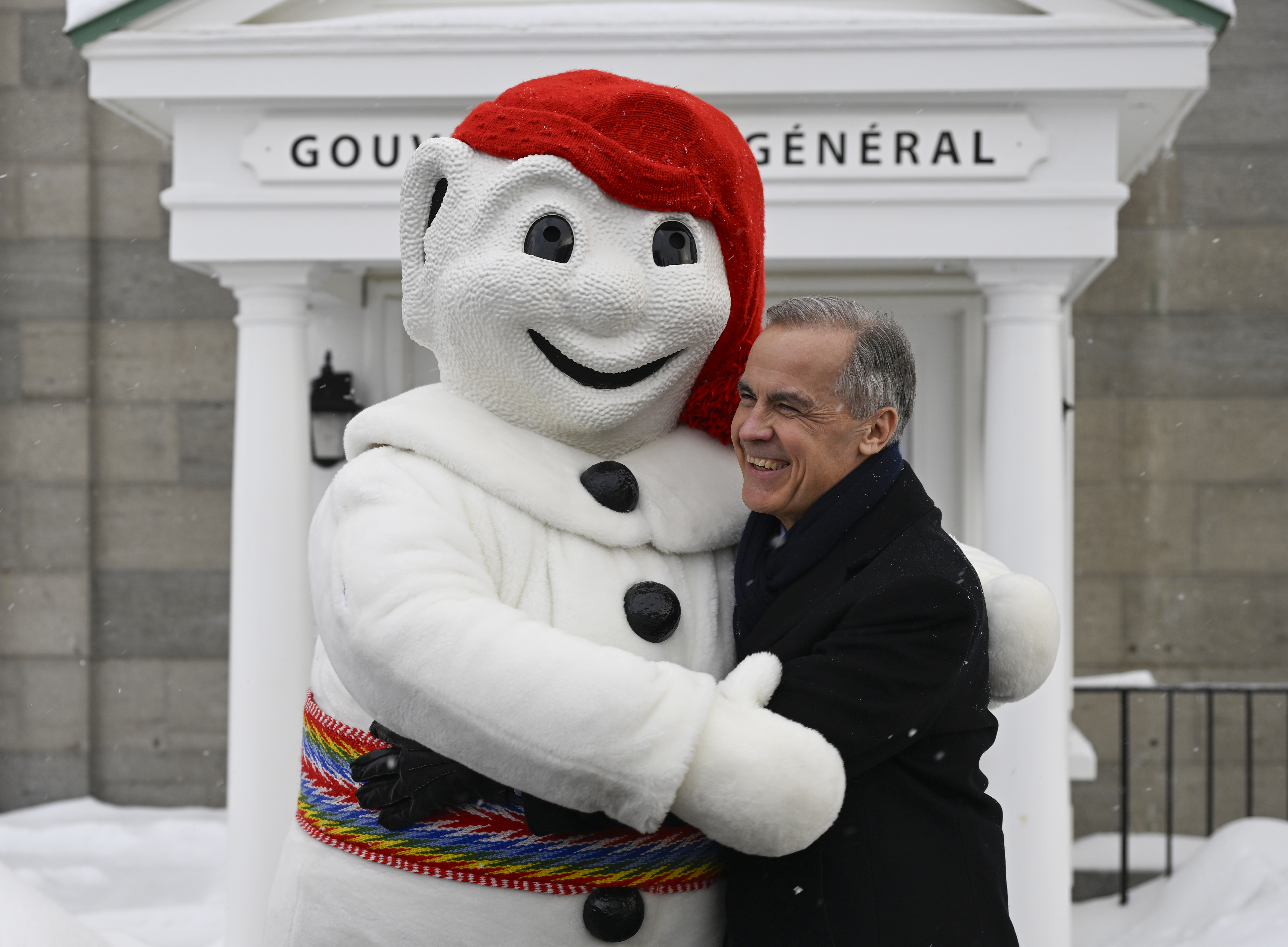 Prime Minister Mark Carney, right, and Bonhomme Carnaval hug