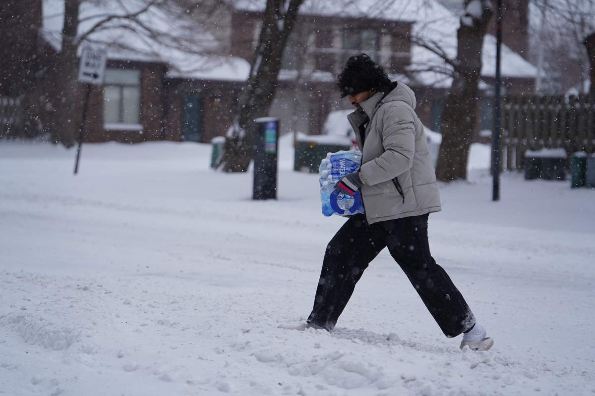 A man carries a pack of water bottles during a snowstorm in downtown Indianapolis, on Sunday, Jan. 25, 2026.