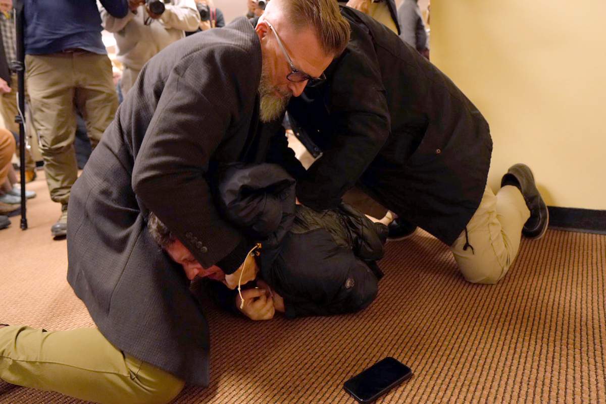 A man is tackled to the ground after spraying an unknown substance on U.S. Rep. Ilhan Omar, D-Minn., during a town hall on Tuesday, Jan. 27, 2026, in Minneapolis.