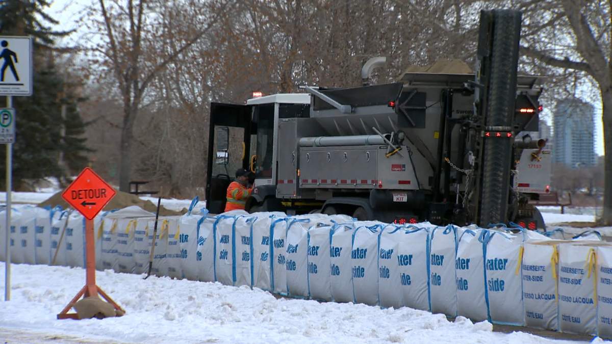 Workers begin to stretch a long line of large sandbags along the Bow River Pathway near the Parkdale community, forming a barrier between homes and businesses, and the buried location of the Bearspaw feeder main.