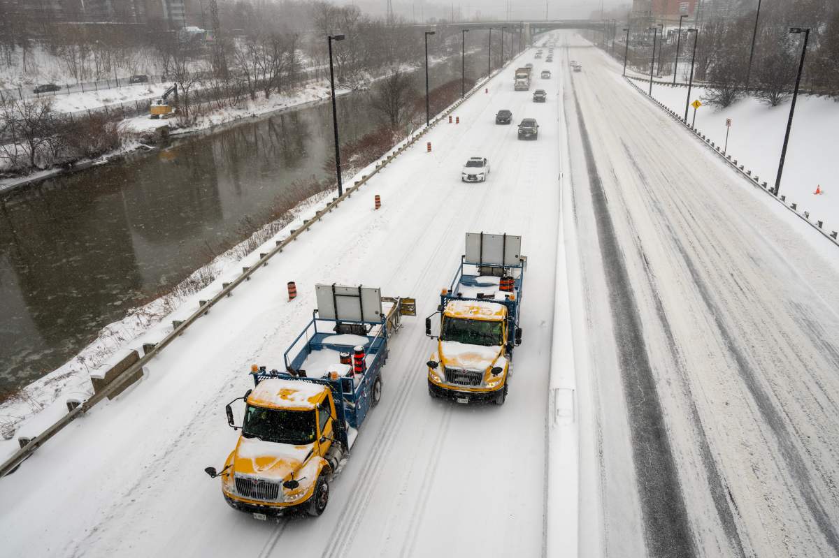 Safety trucks lead the reopening of the Don Valley Parkway during heavy snow in Toronto on Jan. 15, 2026.