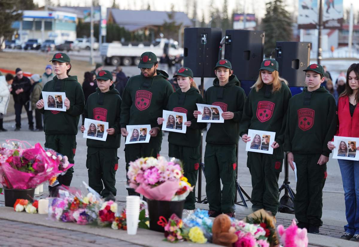 People bring photos of victims to a vigil for the victims of a mass shooting, in Tumbler Ridge, B.C., Friday, Feb. 13, 2026. THE CANADIAN PRESS/Christinne Muschi