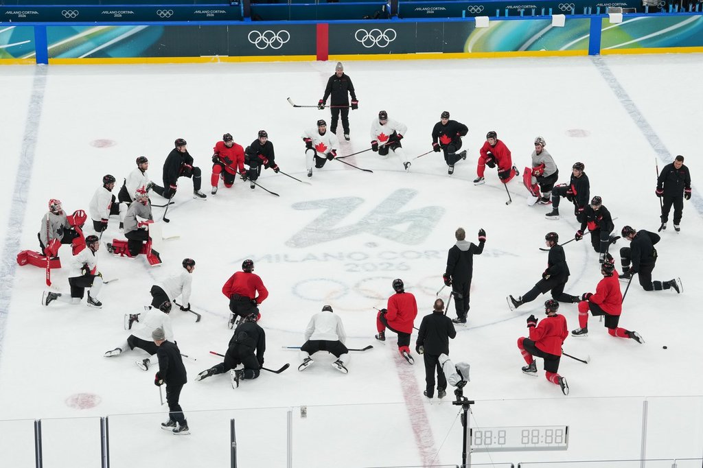 Canada's head coach Jon Cooper, lower right with arm raised, speaks to the team during men's ice hockey practice at the 2026 Winter Olympics, in Milan, Italy, Sunday, Feb. 8, 2026. (AP Photo/Carolyn Kaster).