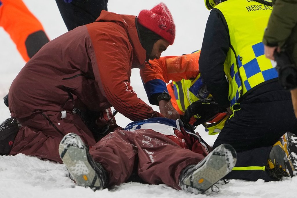 People tend to Canada's Mark McMorris after crashing during a snowboard big air training session at the 2026 Winter Olympics, in Livigno, Italy, Wednesday, Feb. 4, 2026. (AP Photo/Lindsey Wasson).