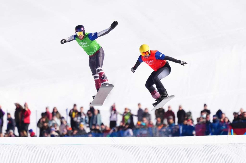 Canada's Eliot Grondin, left, and Austria's Jakob Dusek competes in the mixed snowboard cross team event at the Milano Cortina 2026 Winter Olympic Games in Livigno, Italy on Sunday, Feb. 15, 2026. THE CANADIAN PRESS/Sean Kilpatrick.