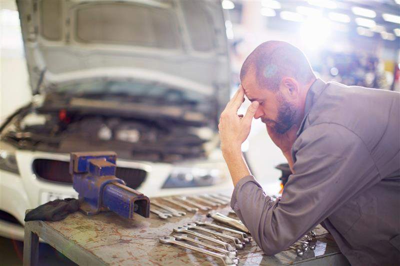 A mechanic rubs his forehead after receiving a severance offer from his boss.