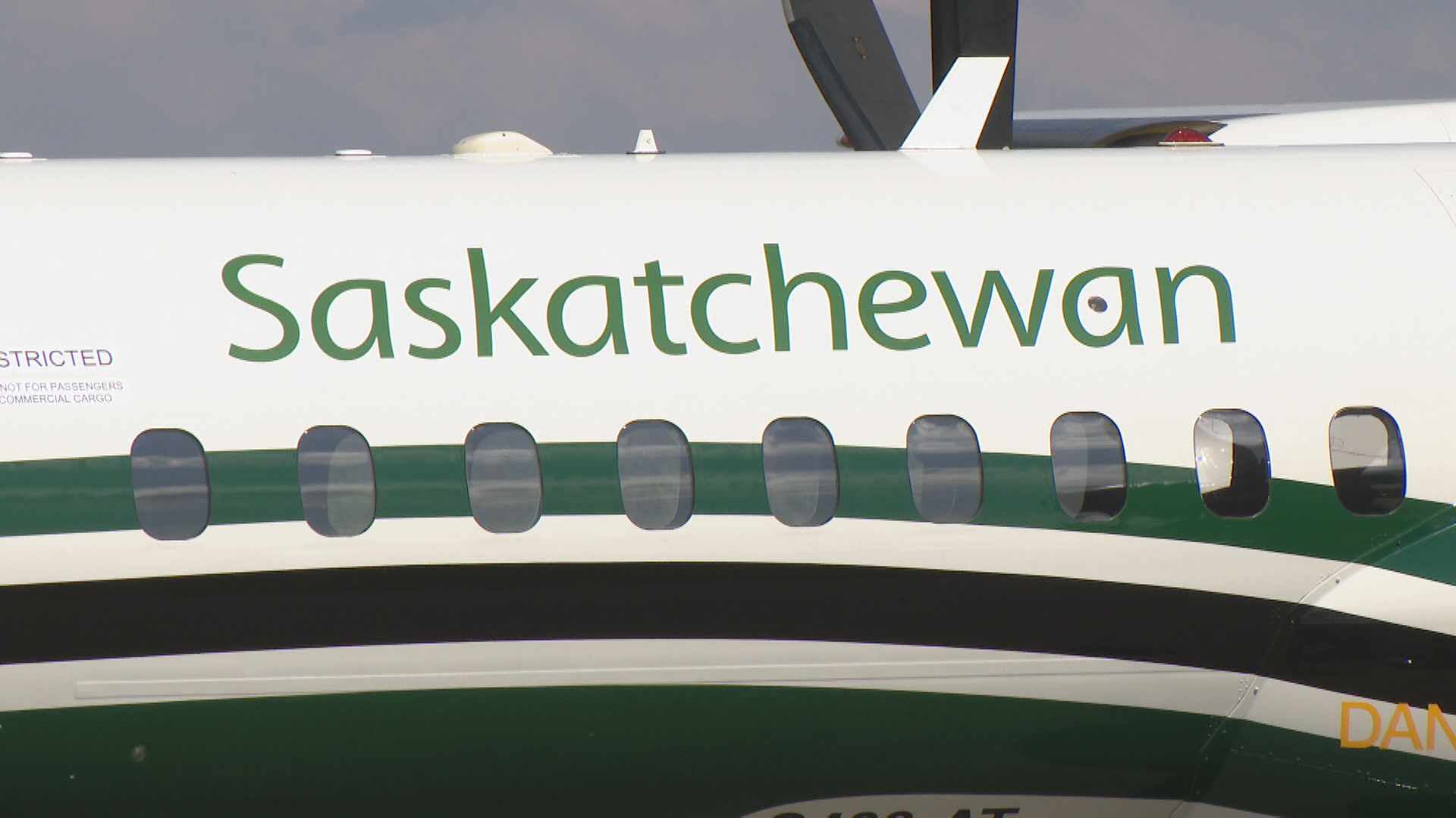 A white plane has green and black stripes with green lettering reading "Saskatchewan" plastered across it.