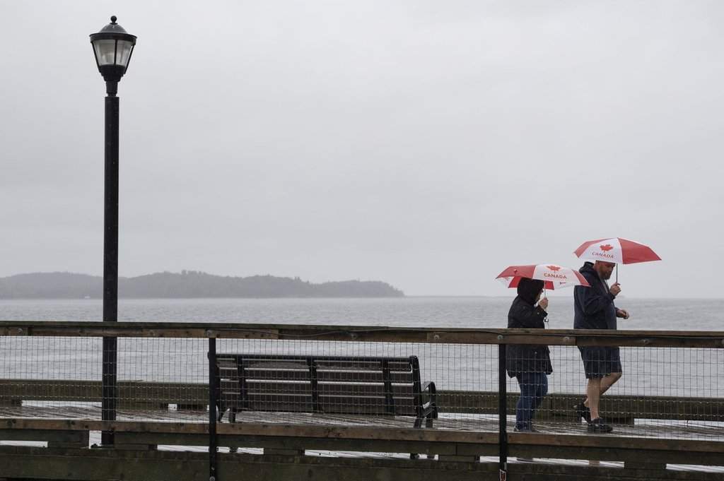 Pedestrians shield themselves with umbrellas while walking along the Halifax waterfront as rain falls ahead of Hurricane Fiona making landfall in Halifax, Friday, Sept. 23, 2022. THE CANADIAN PRESS/Darren Calabrese.