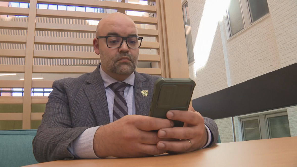 Political scientist Jared Wesley looks at his cellphone