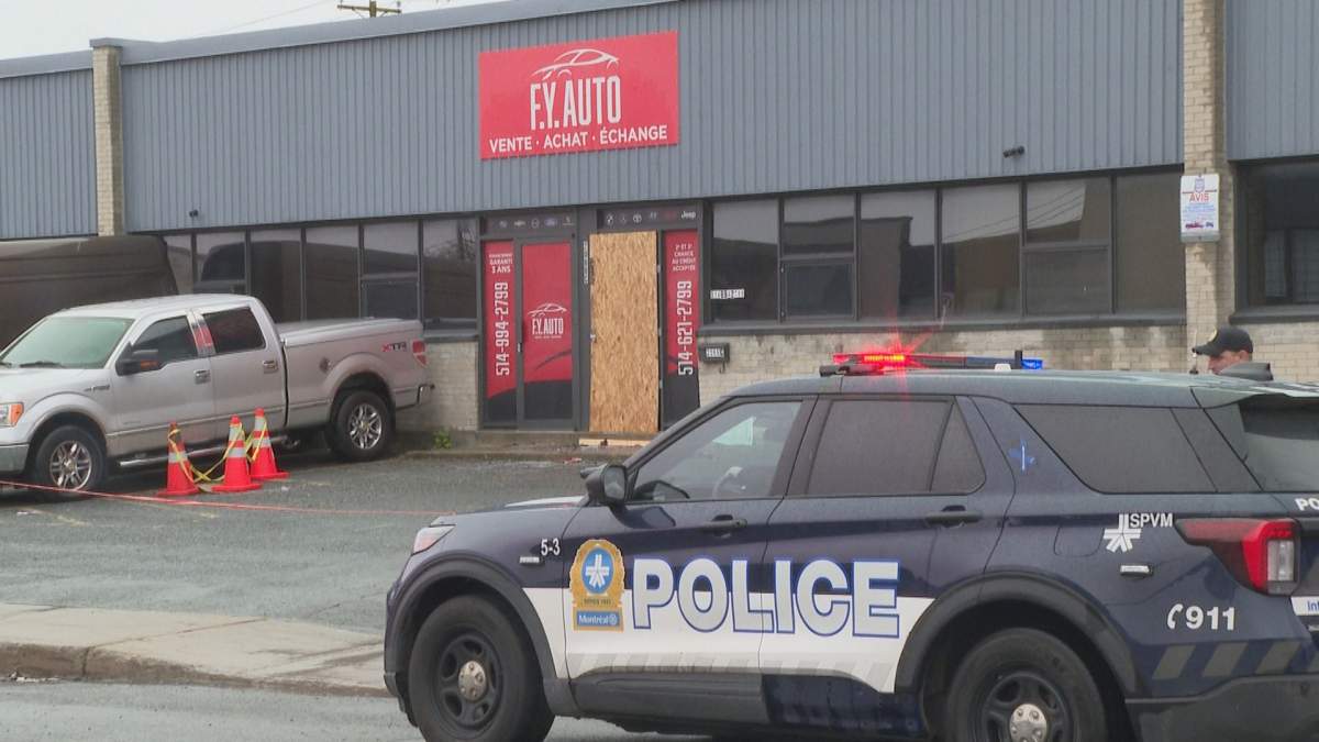 A Montreal police van sits outside a car dealership on May 25 after officers say one or more suspects set fire using incendiary material causing damage to several vehicles. 