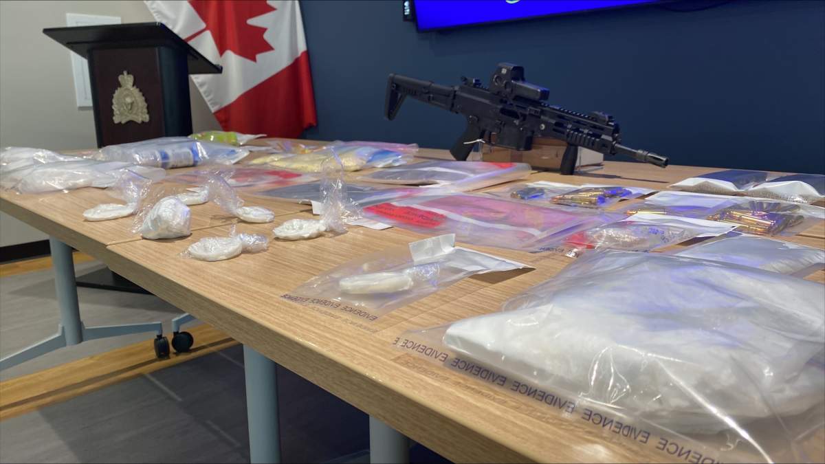 A cache of cocaine, fentanyl, counterfeit Xanax and a semi-automatic rifle are displayed by Cochrane RCMP after a pair of separate busts in May.