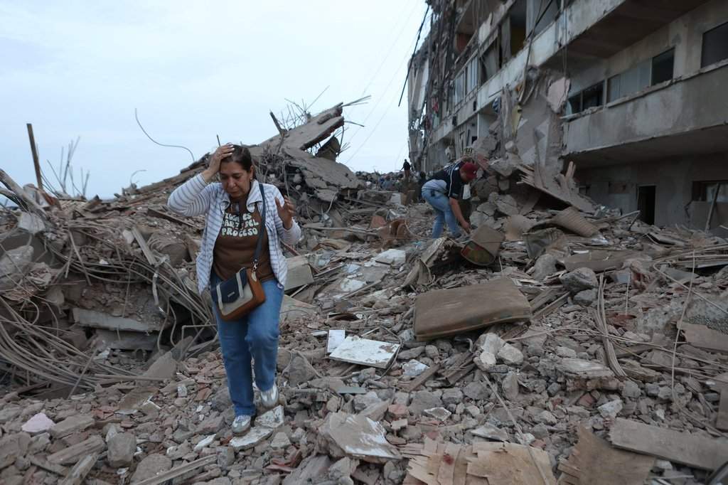 Residents walk among the rubble of building damaged in an earthquake in Catia La Mar, Venezuela, Thursday, June 25, 2026. (AP Photo/Pedro Mattey)