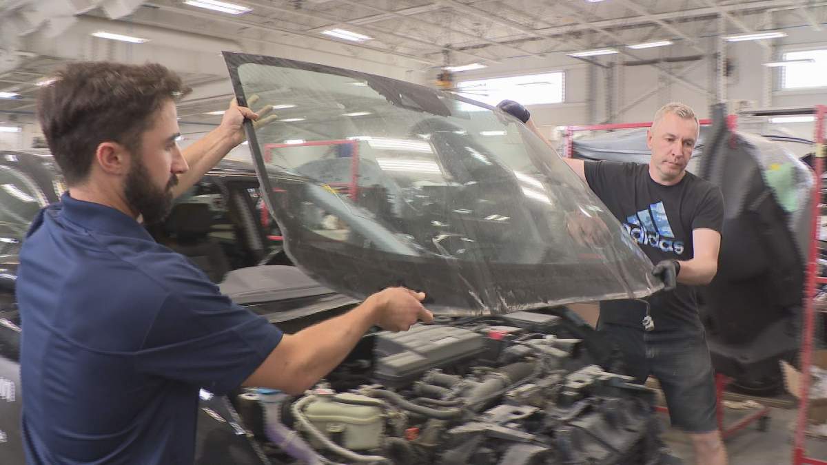 Removing a windshield cracked by hail.