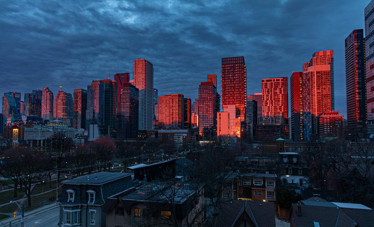 Newly completed condos and other downtown Toronto buildings glow fiery red in the dawn sunlight on Sunday, April 12, 2026. New condo construction in the city has all but ceased in light of low investor and buyer interest. 