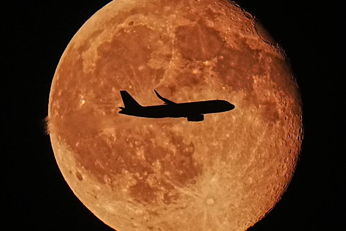 An airplane flies in front of the moon as it rises over Istanbul, Turkey, Friday, July 31, 2026. 