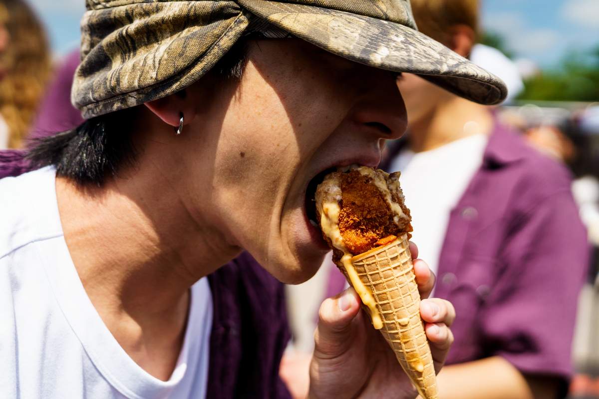 A person takes a bite of the Carnival Cone from Beach Hill Smokehouse Food Truck at the Canadian National Exhibition (CNE) media preview day in Toronto, on Wednesday, Aug. 19, 2026. 