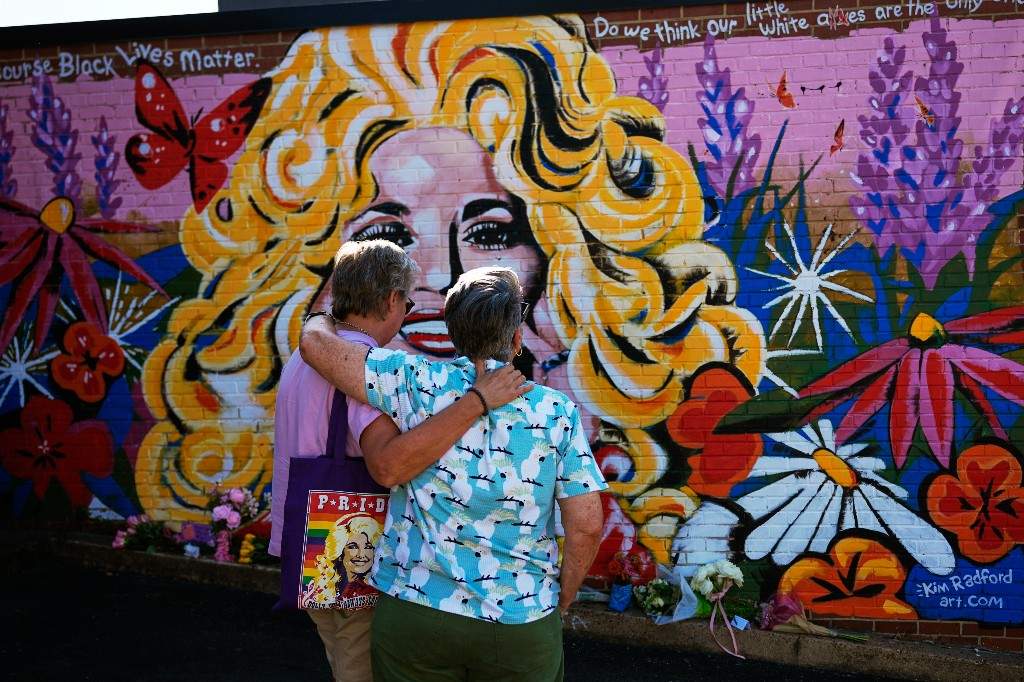 Tracy Ross, left, and Patricia Fonner visit a mural of Dolly Parton on Tuesday, Aug. 25, 2026, in Nashville, Tenn.
