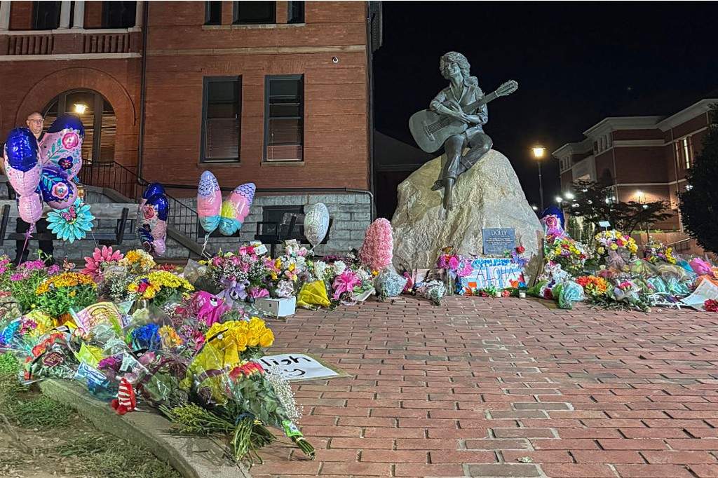 The bronze statue of late US singer-songwriter Dolly Parton is seen surrounded by flowers and balloons placed by fans outside the Sevier County Courthouse in downtown Sevierville, Tennessee on August 25, 2026.
