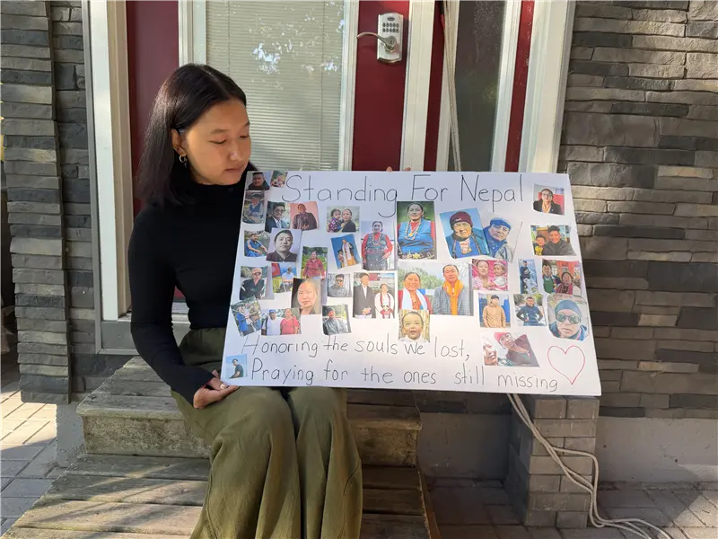 Ang Faulkner holds up photos of her missing relatives and neighbours. She says the poster represents less than five per cent of the people her family has lost.