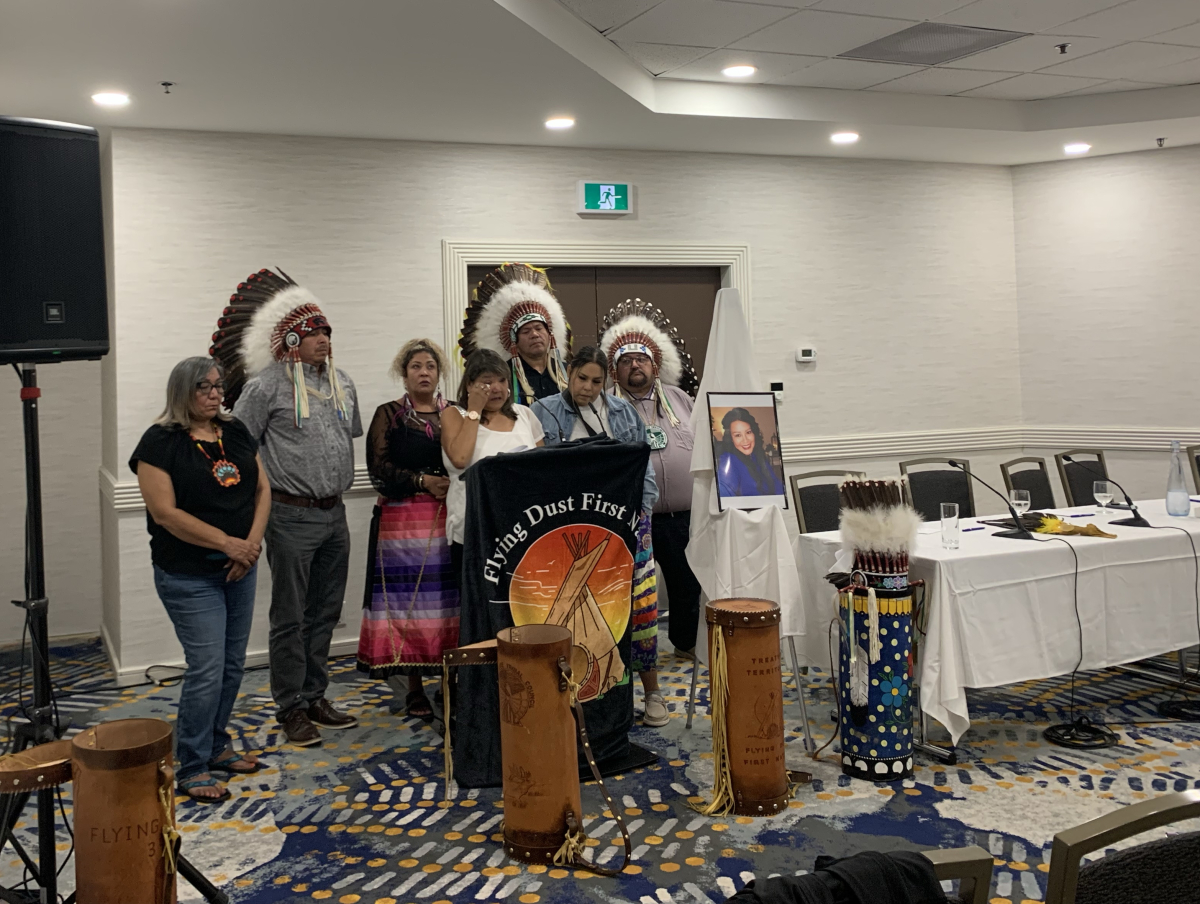 Photo of Debbie Bear, the Meadow Lake Tribal Council leadership and Flying Dust First Nation leadership at a podium sharing Chelsea's story at a news conference.