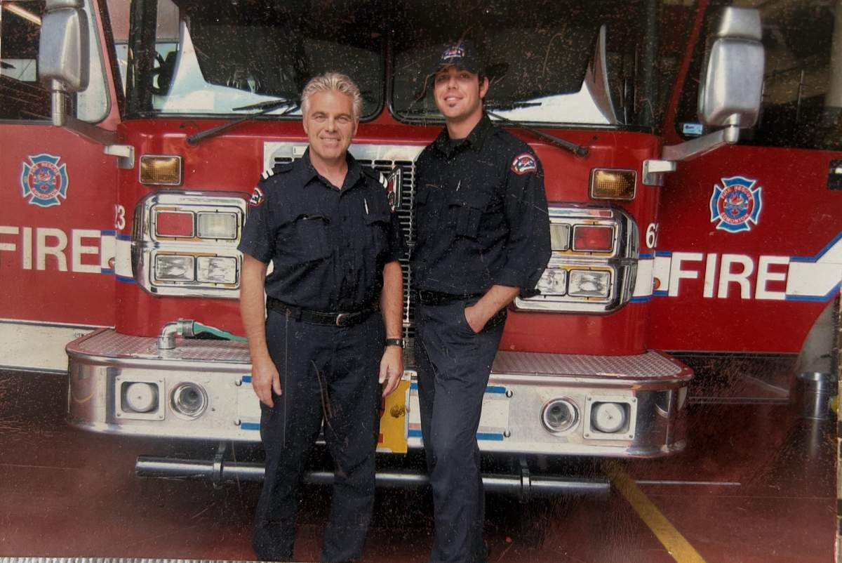 Two firefighters stand in front of an Edmonton Fire Rescue Services Truck