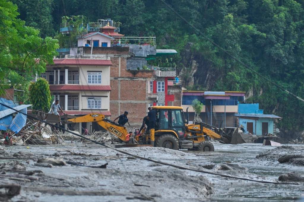 Rescuers use earthmovers to reach submerged houses after flash flooding along the Trishuli River in Nepal's Nuwakot district, Wednesday, Aug. 26, 2026.