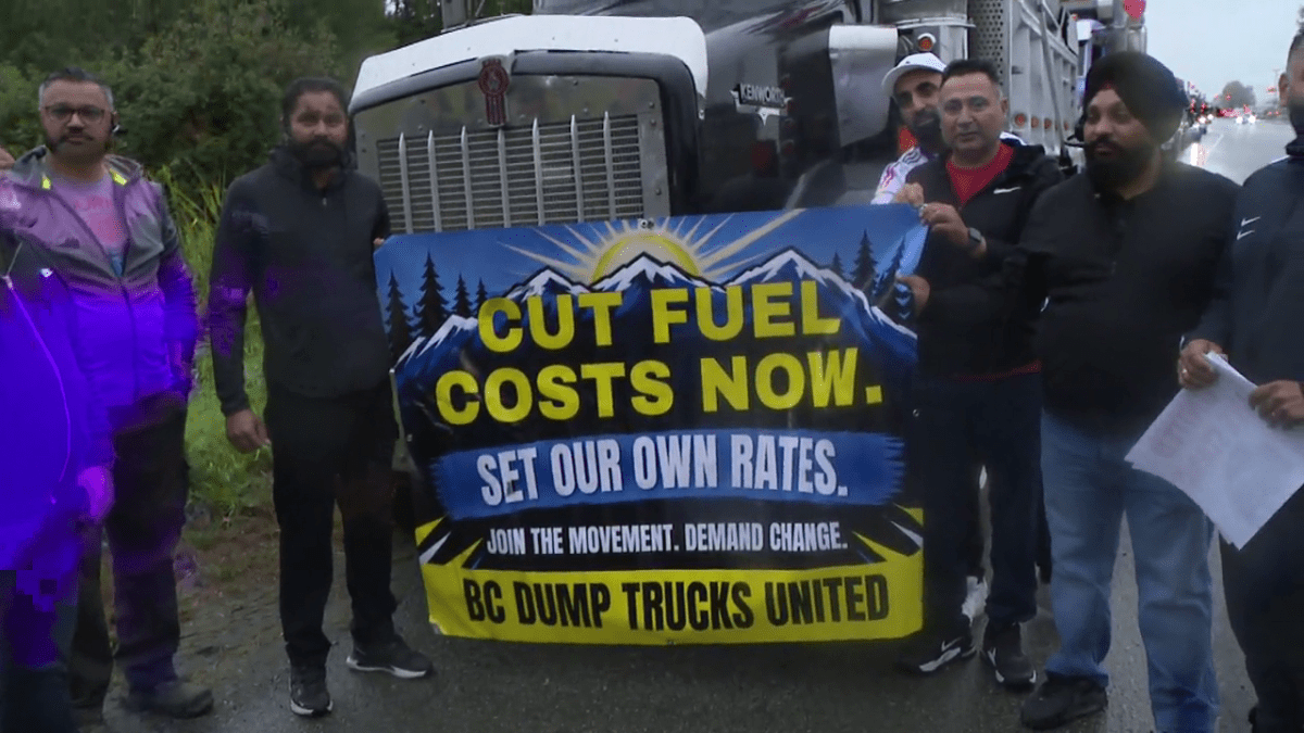 Truckers hold up a sign ahead of the protest convoy starting in Surrey on Friday morning.