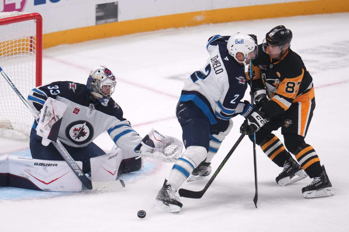 Pittsburgh Penguins' Sidney Crosby (87) can't get off a shot in front of Winnipeg Jets goaltender Clay Stevenson (33) with Dylan DeMelo (2) defending during the first period of an NHL hockey game in Pittsburgh, Monday, Oct. 5, 2026. (AP Photo/Gene J. Puskar).
