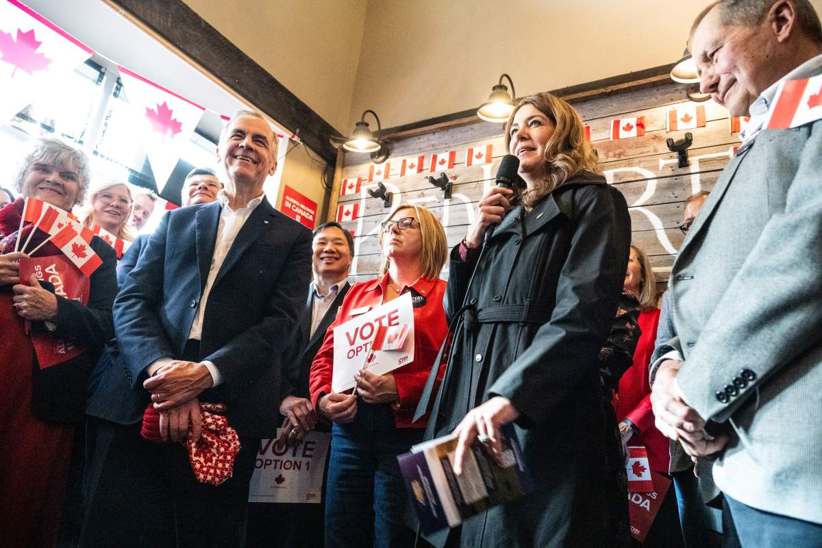 Prime Minister Mark Carney attends a national unity rally in Red Deer alongside, from left, Monte Solberg, Alberta Premier Danielle Smith, and former Premier Ed Stelmach on Friday, Oct. 16, 2026.