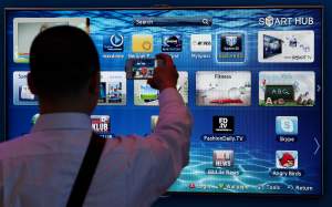 A man takes a picture with his cell phone in front of a smart TV at the IFA consumer electronics fair in Berlin, Germany, Friday, Aug. 31, 2012. (AP Photo/Michael Sohn)